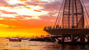 Eine Brücke mit Fußgängerweg und Booten im Wasser bei Sonnenuntergang.