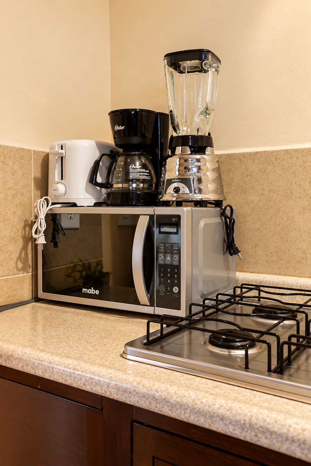 Een kitchenette met een magnetron, koffiezetapparaat en blender op het aanrecht.
