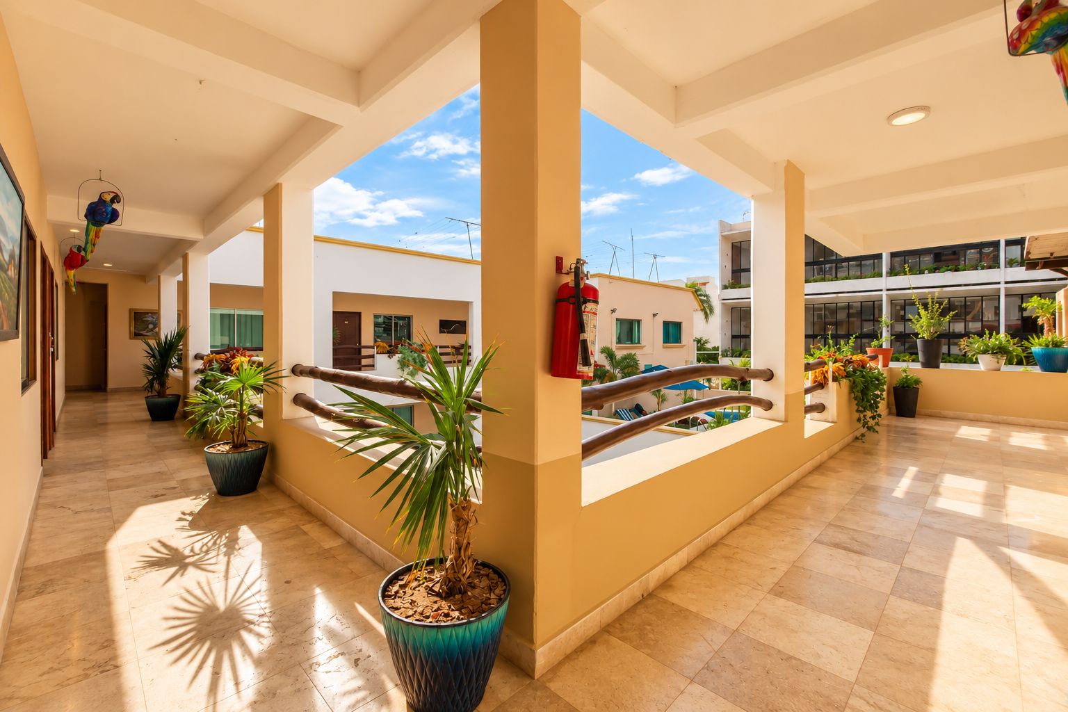 A spacious indoor area with potted plants, a balcony with a view, and a well-lit ceiling.