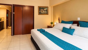 Une chambre d’hôtel avec un lit, une table de chevet, un tableau et une porte donnant sur une autre pièce.
