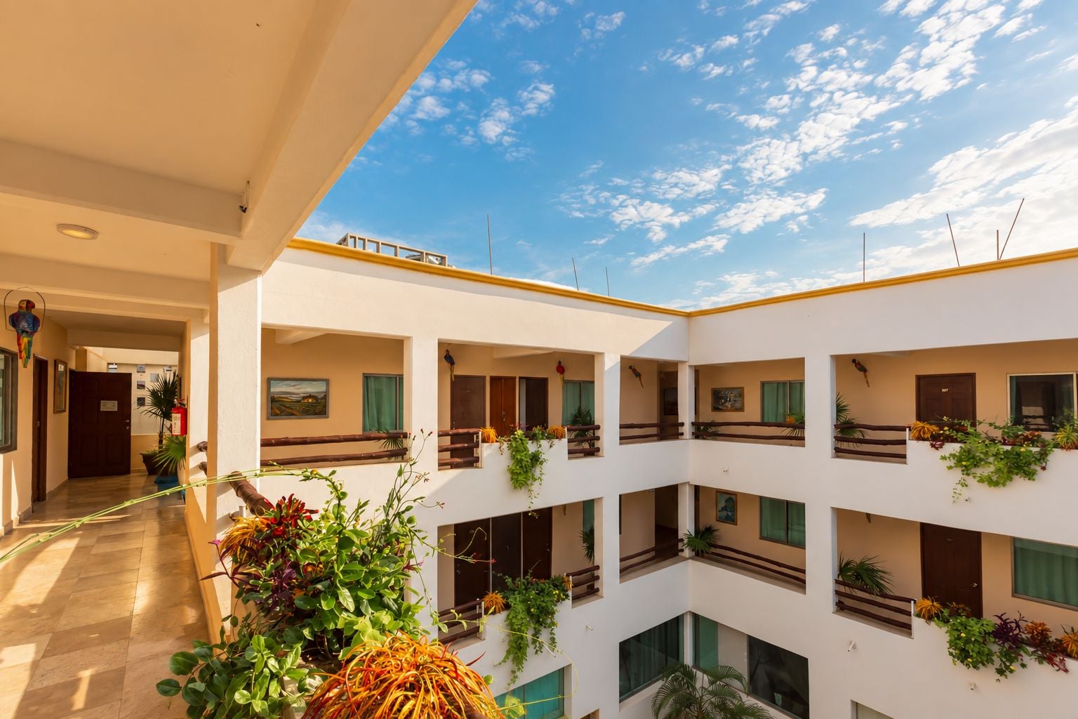 Un edificio de varios niveles con balcones, cada uno con plantas y vista al cielo.