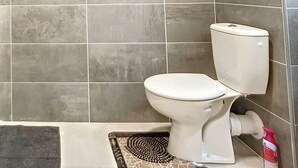 A bathroom with a glass shower enclosure, a toilet, and a small rug. - Superb T2 Splendid view Ajaccio (AJACCIO)