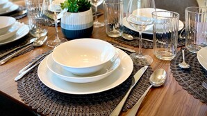 A dining table set with plates, glasses, and cutlery, with a potted plant and a framed picture on the wall. - Ultra-Chic Modern Mid-Century Home in Bethany (Portland)