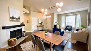 A modern living room with a dining area, fireplace, and large windows. - Ultra-Chic Modern Mid-Century Home in Bethany (Portland)