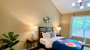 A bedroom with a bed, two bedside tables, a nightstand, a potted plant, a decorative wall piece, and a ceiling light fixture. - Ultra-Chic Modern Mid-Century Home in Bethany (Portland)