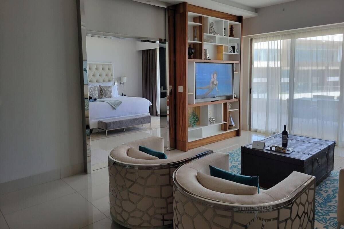 Een moderne hotelkamer met een bed, een televisie, een bijzettafeltje en een zithoek.
