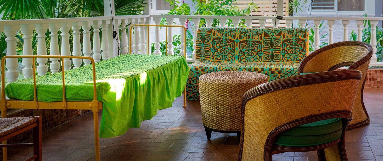 Una habitación con cama, sofá y sillas de mimbre.