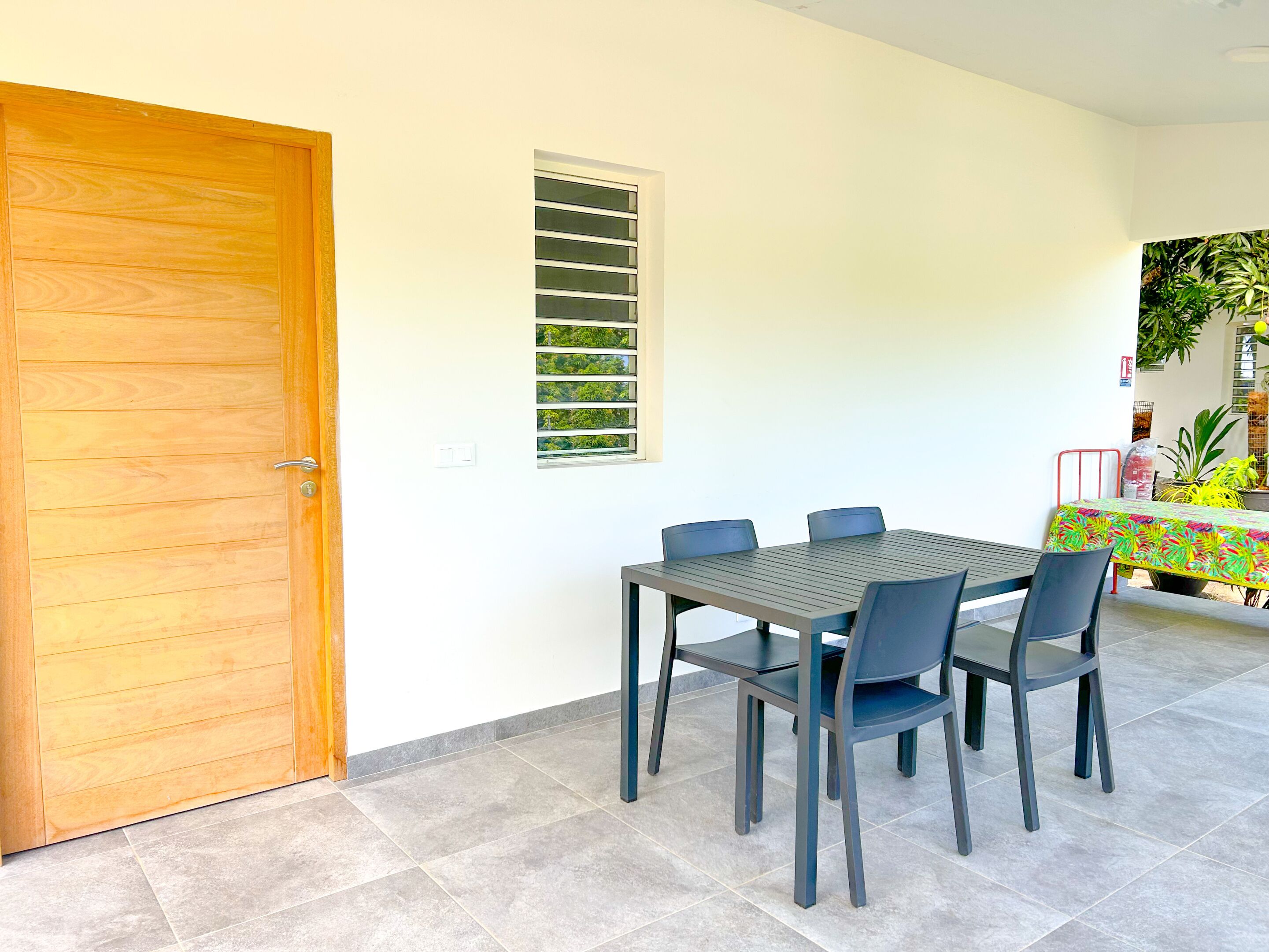 Uma sala de jantar com porta de madeira, janela com persianas e uma mesa com cadeiras.