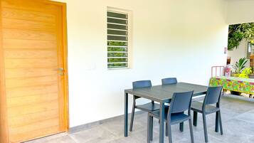 Uma sala de jantar com porta de madeira, janela com persianas e uma mesa com cadeiras.