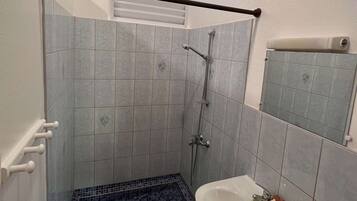 Une salle de bain avec une douche, un lavabo et une fenêtre.