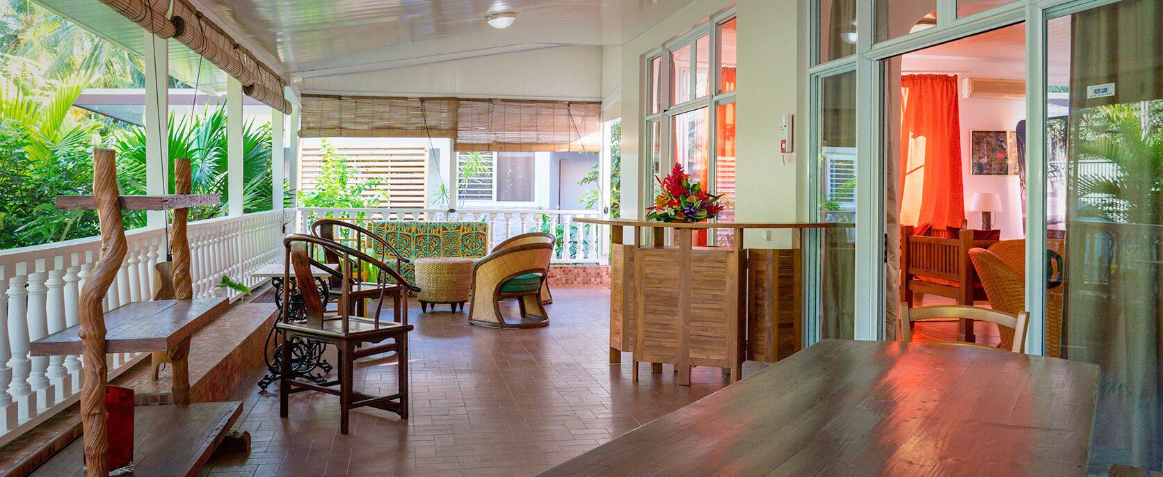Un banco y sillas de madera en una habitación con vistas a la vegetación.