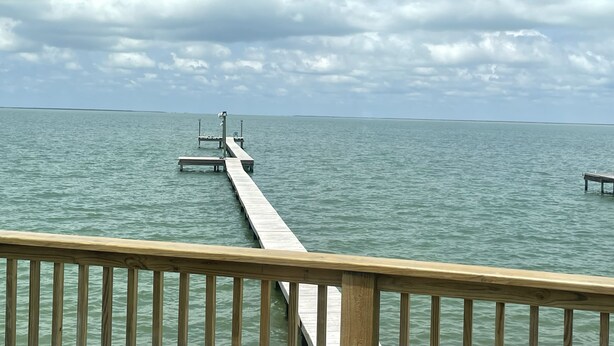 A wooden pier extending into calm water under a cloudy sky.