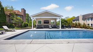 A swimming pool with lounge chairs and a covered seating area. - Amazing Home Near IU's Campus with INDOOR Basketball Gym & Outdoor Pool/Hot tub (Bloomington)