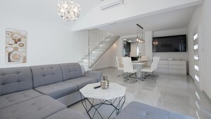 A modern living room with a grey sectional sofa, a white coffee table, and a chandelier. - Amazing home in Zmijavci (Zmijavci)