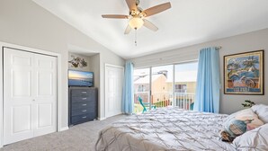 A bedroom with a bed, a ceiling fan, a dresser, a window with curtains, and a painting on the wall. - Gulf Bliss: 5MinWalkToBeach,Pool,Yard,CloseToAll (Miramar Beach)