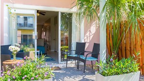 An outdoor patio with wicker furniture, a glass door leading to a balcony, and potted plants. - Gulf Bliss: 5MinWalkToBeach,Pool,Yard,CloseToAll (Miramar Beach)