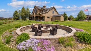 A large house with a fire pit and outdoor seating area surrounded by a stone wall.