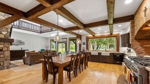 A spacious kitchen with a large island, wooden beams, and a brick oven.