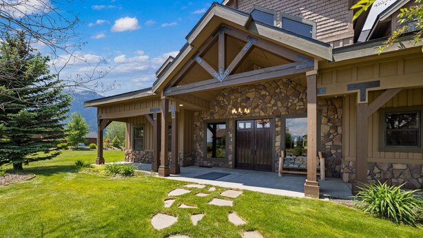 A modern house with a stone facade, a covered porch, and a well-maintained lawn.