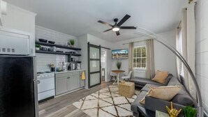 A modern kitchen with white cabinets, a black refrigerator, and a dining area with a round table and sofa. - Lovely 1 BR with King bed Apt 2 (New Bern)