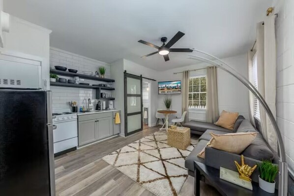 Cozy living space with a kitchenette, sofa, and flat-screen TV.