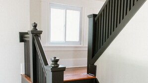 Een houten trap met donkere leuningen en een lamp erboven.