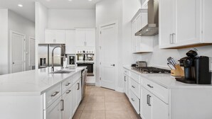 A modern kitchen with white cabinetry, a large island, and a built-in oven.