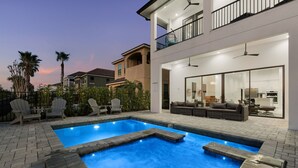 A modern house with a swimming pool, outdoor seating, and a balcony.