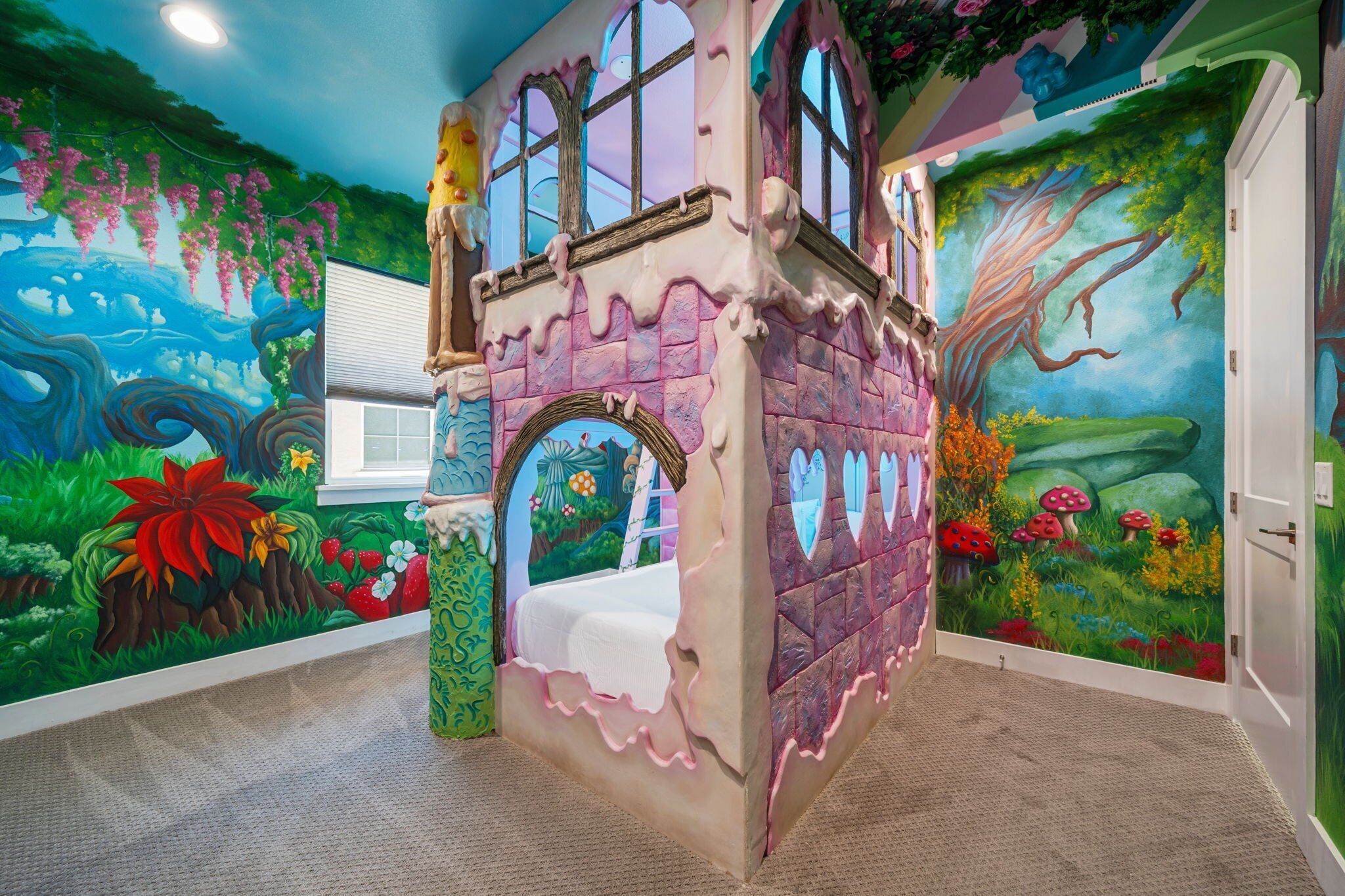 A children's playroom with a castle-themed playhouse, colorful murals, and a window.