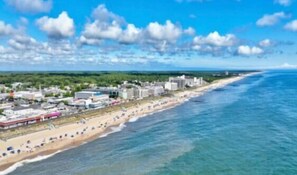 Paisagem costeira com praia, edifícios e céu claro.