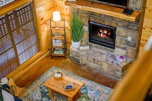 A cozy log cabin interior with a stone fireplace, wooden shelves, and a comfortable seating area. - The Arrington,Outdoor Area,Playset,Hot Tub/Fire Pit (Broken Bow)
