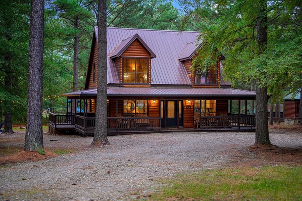A log cabin with a porch, large windows, and a metal roof. - The Arrington,Outdoor Area,Playset,Hot Tub/Fire Pit (Broken Bow)