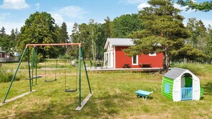 Un parque infantil con columpios y una casita de juegos verde.