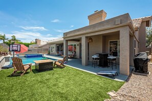 A backyard with a swimming pool, outdoor seating, and a barbecue area.