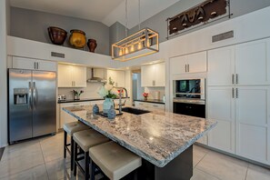 A modern kitchen with a large island, stainless steel appliances, and white cabinetry.