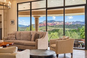 A spacious living room with a large window offering a view of red rock formations and greenery.