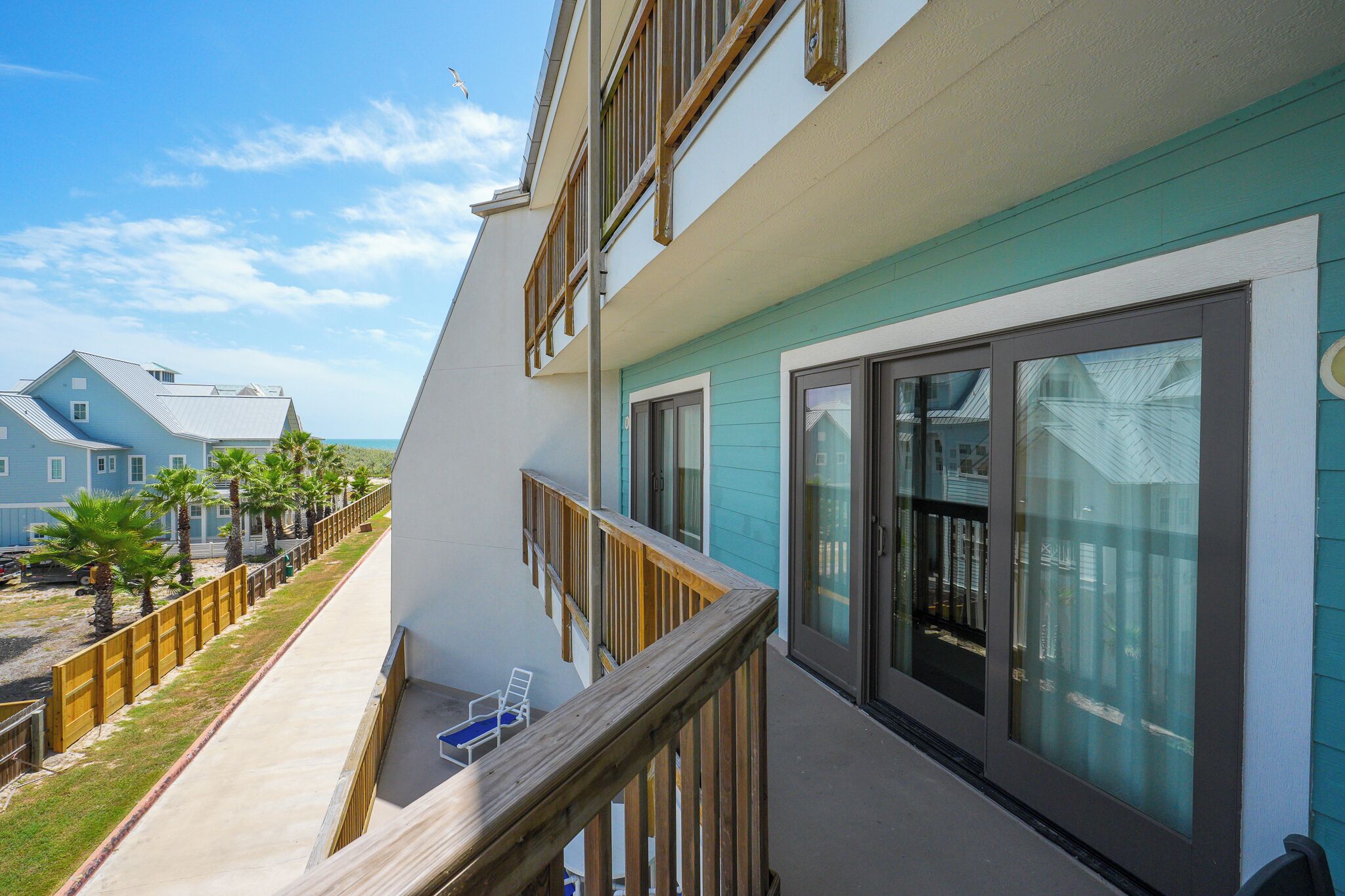 A multi-story building with a balcony, large windows, and a view of the ocean.