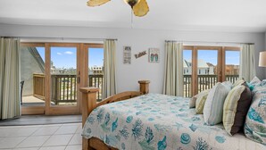 Un dormitorio con cama, cortinas, ventilador de techo y vistas al exterior.