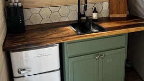 A compact kitchen with a microwave, sink, and green cabinets. - Red Owl Retreat-The Nook. (Bigfork)