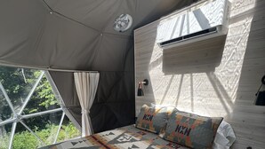 A tented room with a bed, a window, and an air conditioning unit. - Red Owl Retreat-The Nook. (Bigfork)