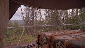 A tent with a metal framework and a bed with a patterned blanket. - Red Owl Retreat-The Nook. (Bigfork)