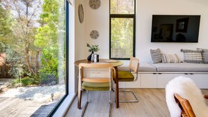 Een moderne woonkamer met een groot raam, een ronde tafel en een bank met kussens.