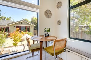 Enjoy a serene view from the large window, with a comfortable seating area featuring a round table and two cushioned chairs.