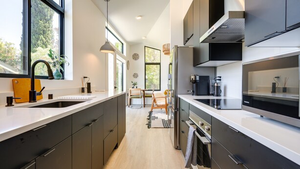 Een moderne keuken met donkere kastjes, een groot raam en uitzicht op het omliggende landschap.