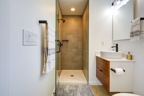 Enjoy a refreshing shower with a clear view, complemented by a convenient vanity and mirror.