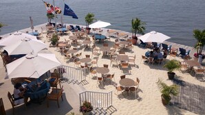 A beachside restaurant with outdoor seating, including tables and chairs, and a view of the ocean.