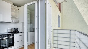 Una cocina moderna con armarios blancos, horno integrado y cafetera.