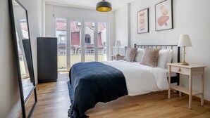Un dormitorio con cama, mesitas de noche, lámpara, espejo y obras de arte en la pared.