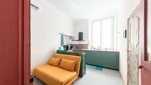 A compact room with a sofa, a kitchenette, and a door. - La Brignoletta - Le Case del Dria - Aquarium suite (Genova)