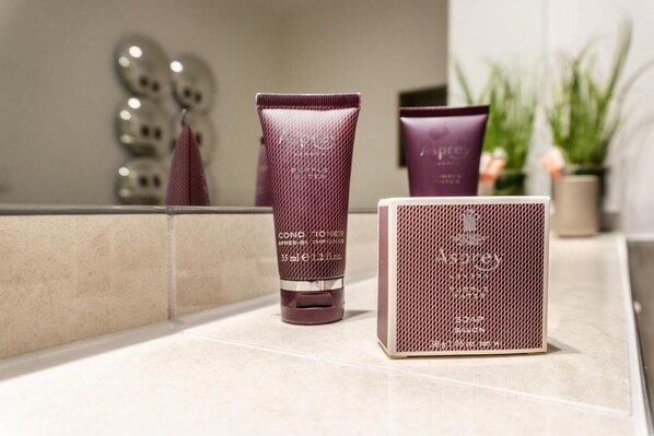 Ein Badezimmer mit Spiegel, einer violetten Shampooflasche, einer violetten Conditionerflasche und einem violetten Seifenstück auf der Ablagefläche.